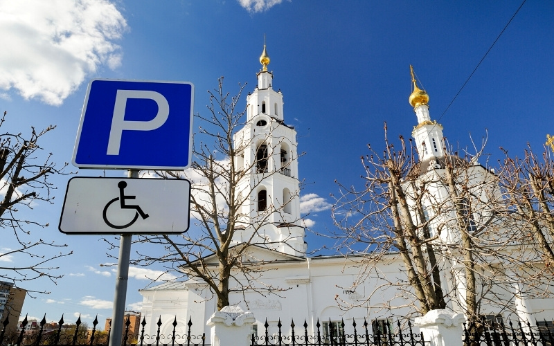 Disabled parking space in front of a white orthodox church in Russia. Accessibility is one of the benefits when you travel locally.